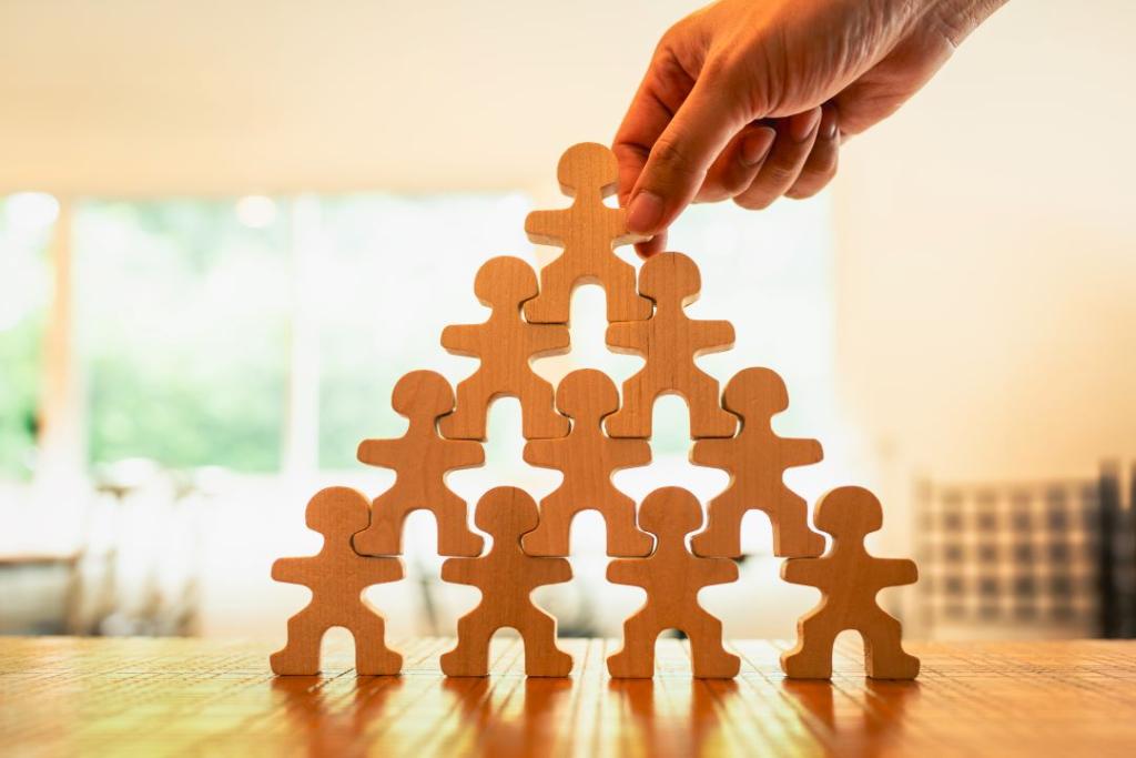 wooden people stacked in a pyramid with a hand placing the top piece
