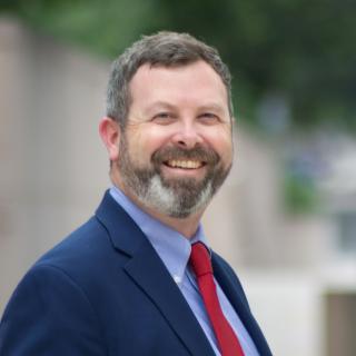 Headshot of Keith Cummins wearing a blue suit and red tie.